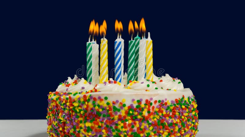 White birthday cake with candy sprinkles multi-colored candles on dark blue background. White birthday cake with candy sprinkles multi-colored candles on dark blue background.