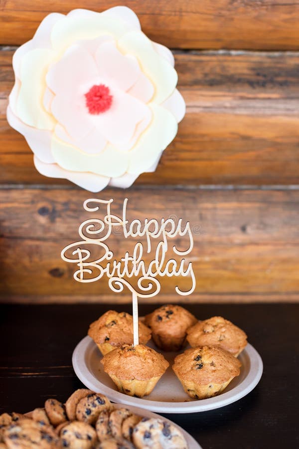 Birthday cakes and muffins with wooden greeting sign on rustic background. Wooden sing with letters Happy Birthday and
