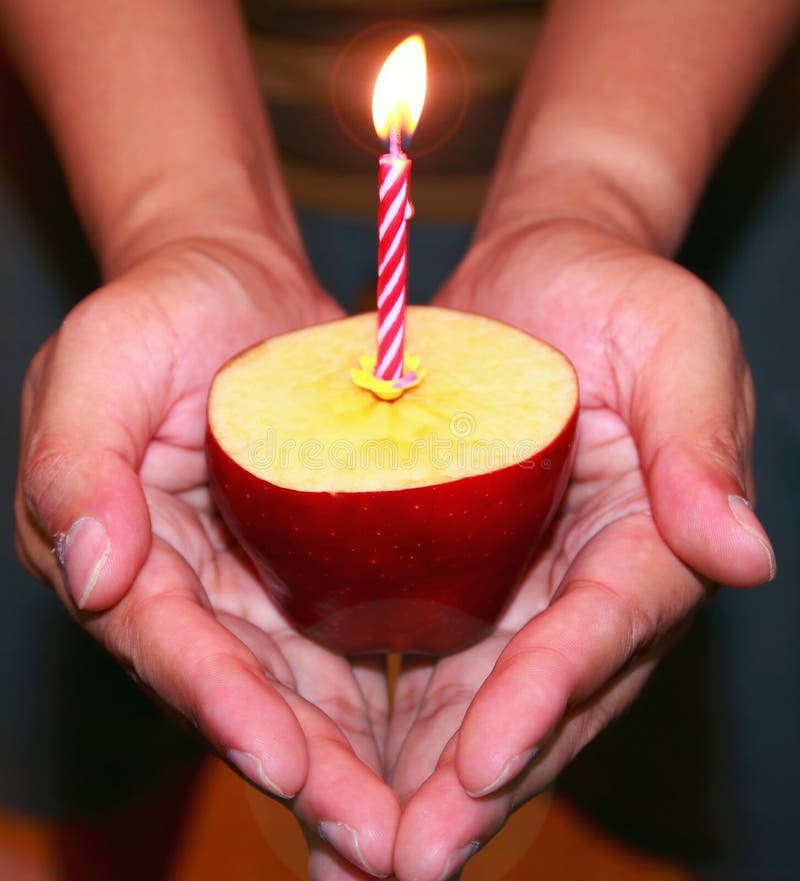 Birthday candle and apple in hand