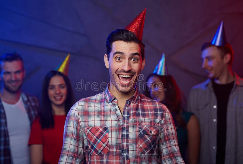 Birthday surprise. Surprised young men in birthday-cap and his friends on background stock photos Birthday surprise. Surprised young men in birthday-cap and his friends on background stock photos