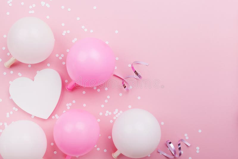 Birthday or wedding mockup with white heart shape, confetti and pastel balloons on pink table top view. Flat lay composition.