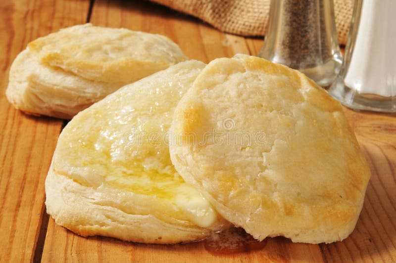 Hot buttered biscuits on a rustic wooden table. Hot buttered biscuits on a rustic wooden table
