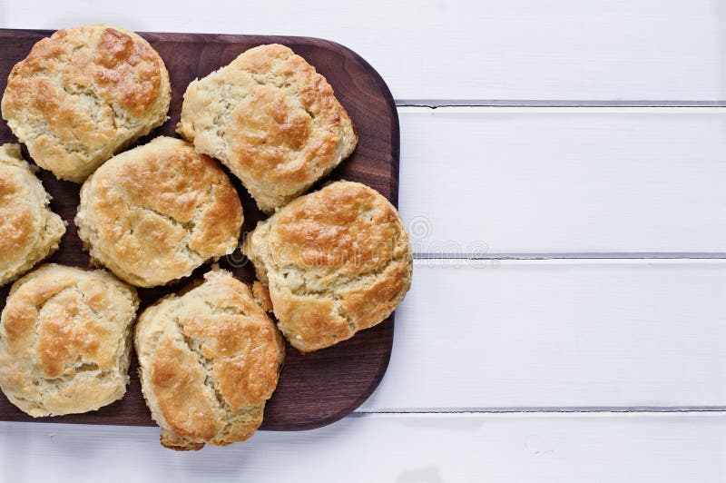 Fresh buttermilk southern biscuits or scones over a white table shot from above. Top view. Fresh buttermilk southern biscuits or scones over a white table shot from above. Top view