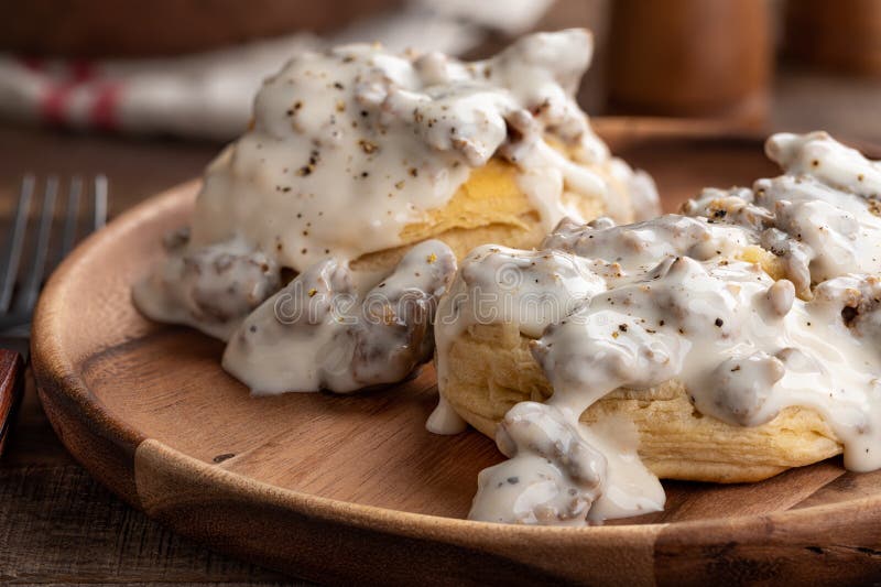 Closeup of biscuits and creamy sausage gravy on a wooden plate. Closeup of biscuits and creamy sausage gravy on a wooden plate