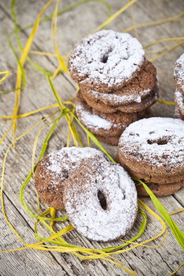 Biscotti di pepita di cioccolato al forno freschi con le pile della polvere dello zucchero sulla tavola di legno immagine stock libera da diritti Biscotti di pepita di cioccolato al forno freschi con le pile della polvere dello zucchero sulla tavola di legno immagine stock libera da diritti