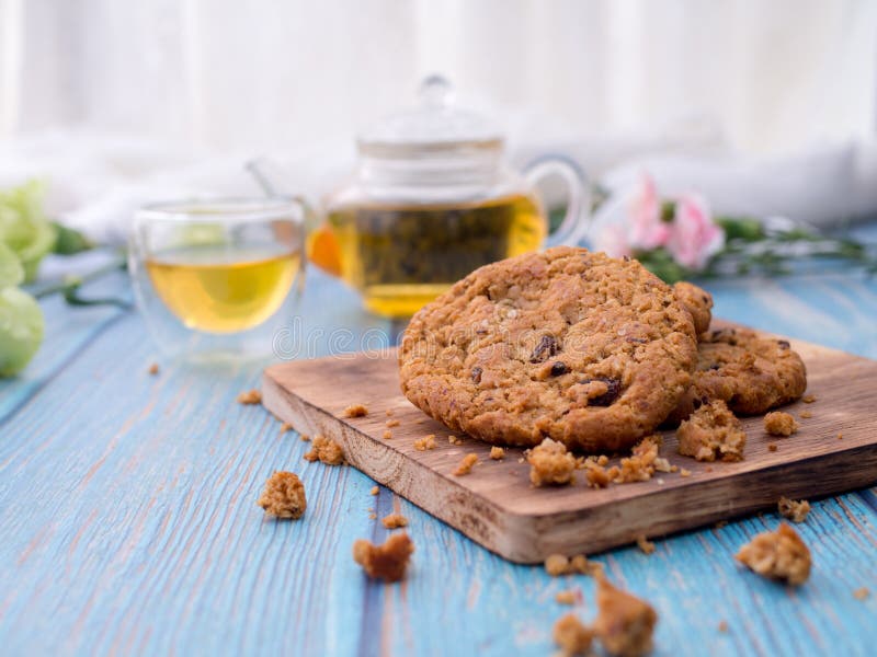 Biscotti di pepita di cioccolato saporiti impilati su un bordo servito con tè e la teiera sulla tavola di legno blu Spuntini casa immagine stock libera da diritti Biscotti di pepita di cioccolato saporiti impilati su un bordo servito con tè e la teiera sulla tavola di legno blu Spuntini casa immagine stock libera da diritti
