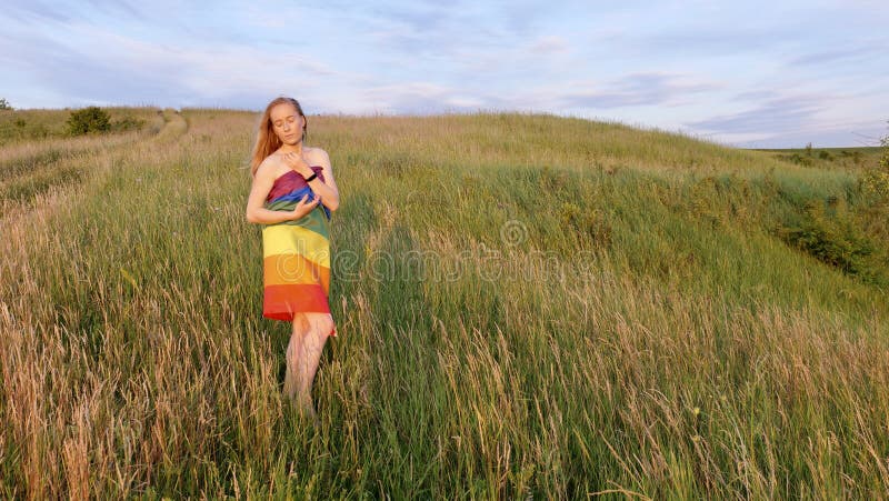 Woman lesbian with LGBT flag on a green field stock image