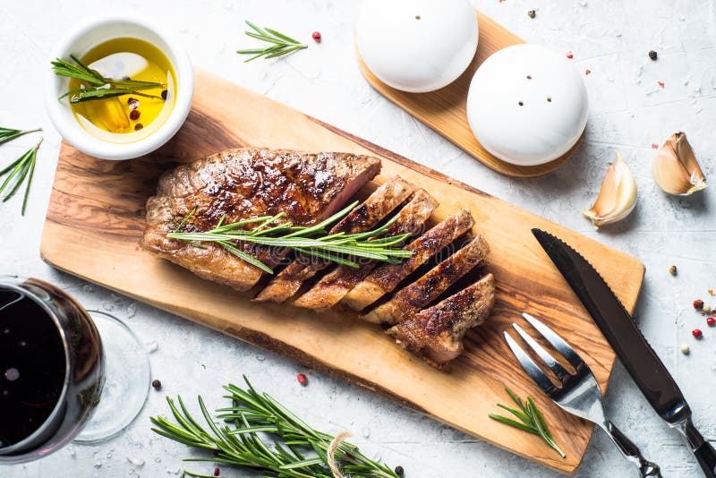Bistecca arrostita dello striploin del manzo con il vetro del vino rosso immagine stock libera da diritti Bistecca arrostita dello striploin del manzo con il vetro del vino rosso immagine stock libera da diritti