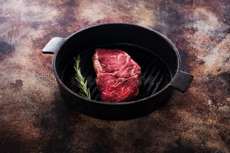 Bistecca cruda del ribeye su una pentola della ghisa immagine stock Bistecca cruda del ribeye su una pentola della ghisa immagine stock