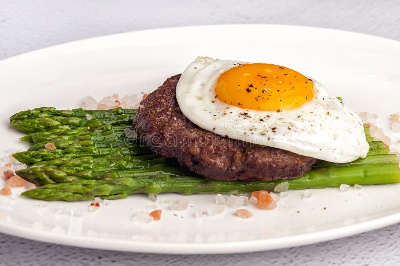 Bistecca da manzo tritato con le uova fritte e l'asparago verde fresco fotografia stock Bistecca da manzo tritato con le uova fritte e l'asparago verde fresco fotografia stock