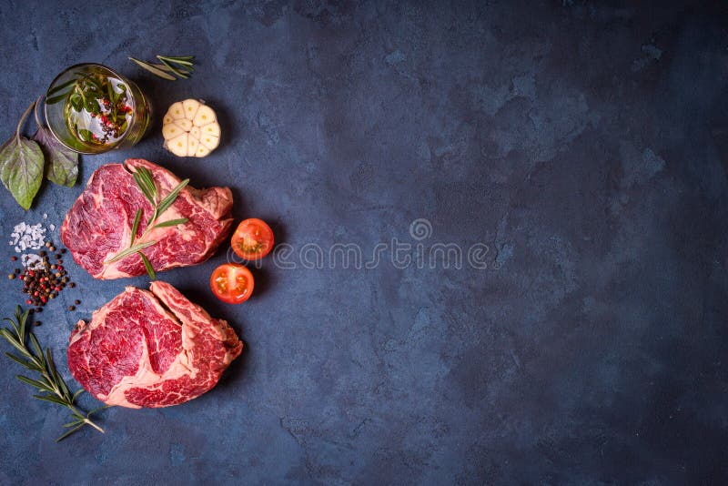Bistecca della carne cruda su fondo concreto rustico pronto alla torrefazione fotografia stock Bistecca della carne cruda su fondo concreto rustico pronto alla torrefazione fotografia stock