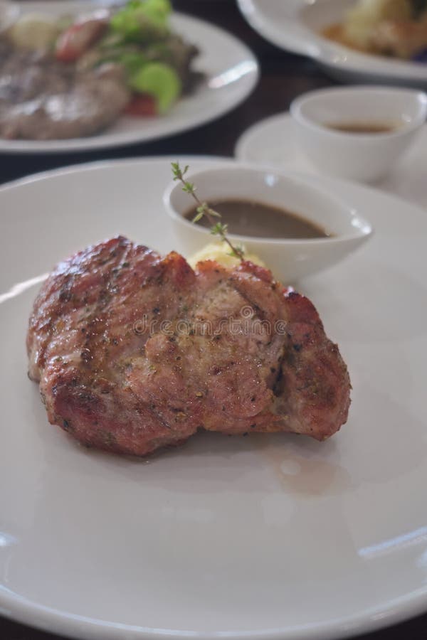 Bistecca della carne di maiale con la patata di poltiglia sul piatto bianco fotografia stock libera da diritti Bistecca della carne di maiale con la patata di poltiglia sul piatto bianco fotografia stock libera da diritti