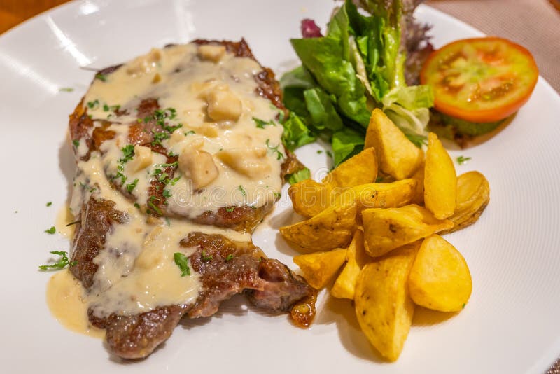 Bistecca di manzo saporita con salsa di funghi e le verdure cremose fotografia stock libera da diritti Bistecca di manzo saporita con salsa di funghi e le verdure cremose fotografia stock libera da diritti