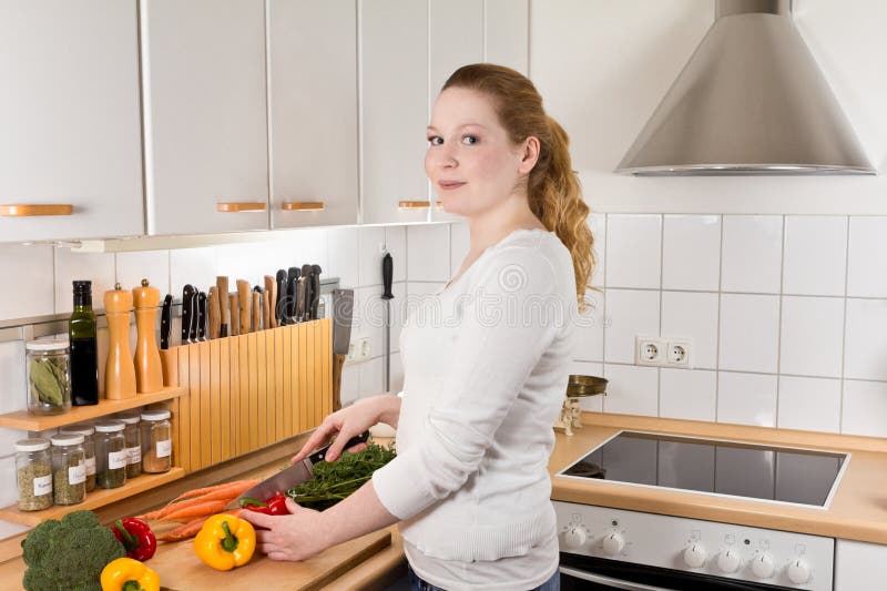 Bitande grönsaker för glat kvinnakök arkivbild