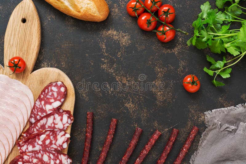 Bitande olika korvar med tomater, bagett på en mörk bakgrund, utrymme för text ovanför sikt royaltyfri foto Bitande olika korvar med tomater, bagett på en mörk bakgrund, utrymme för text ovanför sikt royaltyfri foto