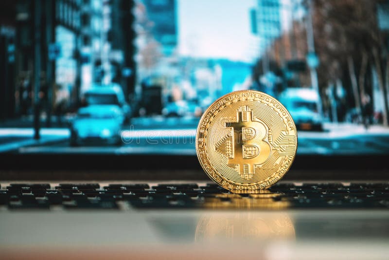 Amsterdam,The Netherlands 05/10/2019. Bitcoin standing on a notebook, modern office building on screen in the background, cryptocurrency, blockchain.
