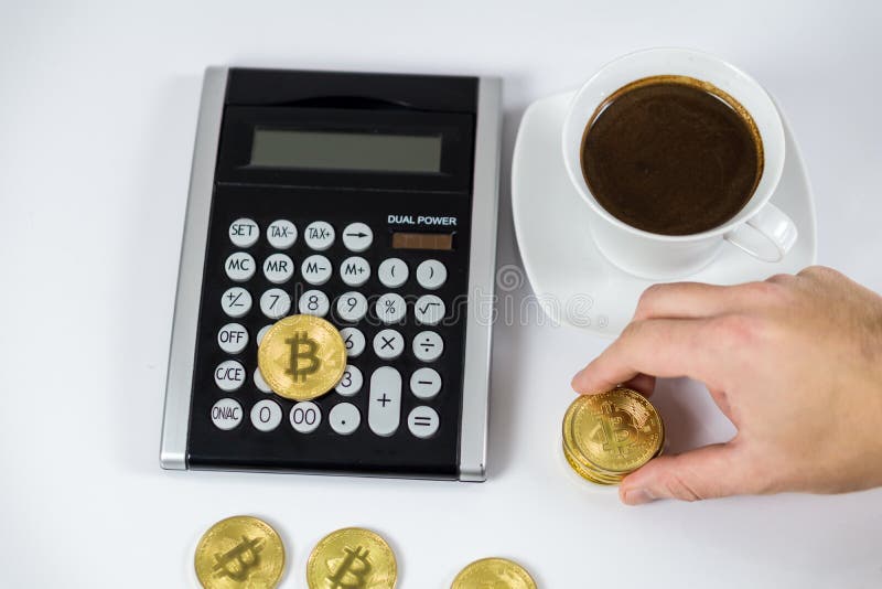Bitcoin dourado guardado à mão na calculadora preta ao lado do café, conceito do cryptocurrency foto de stock royalty free Bitcoin dourado guardado à mão na calculadora preta ao lado do café, conceito do cryptocurrency foto de stock royalty free
