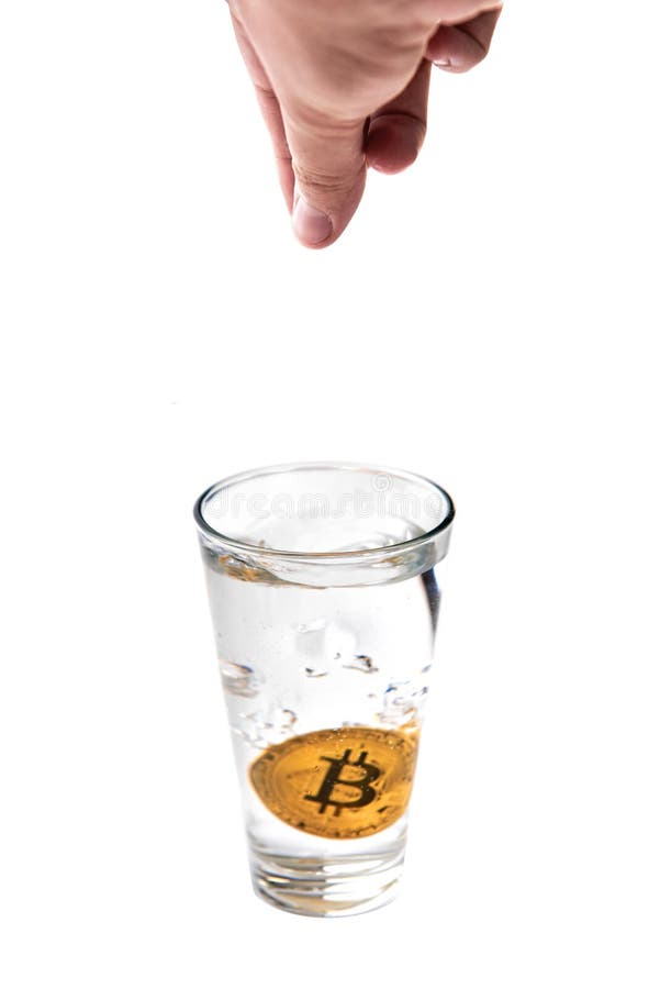 Bitcoin is dropped into a glass of water with woman’s hand. Isolated on white background. Bitcoin is dropped into a glass of water with woman’s hand. Isolated on white background.