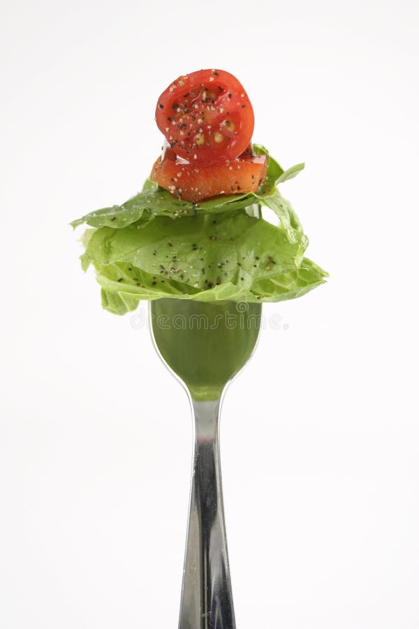 Ensalada, pimienta, tomate sobre el tenedor.