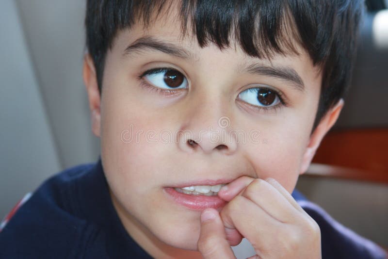 Pequeno chico mordiendo, afuera de preocupaciones o malo hábito.