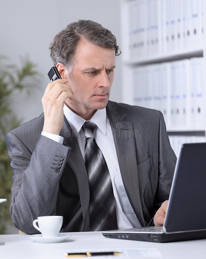 Biznesmen ma rozmowy telefonicza rozmowę przy miejscem pracy obraz royalty free Biznesmen ma rozmowy telefonicza rozmowę przy miejscem pracy obraz royalty free