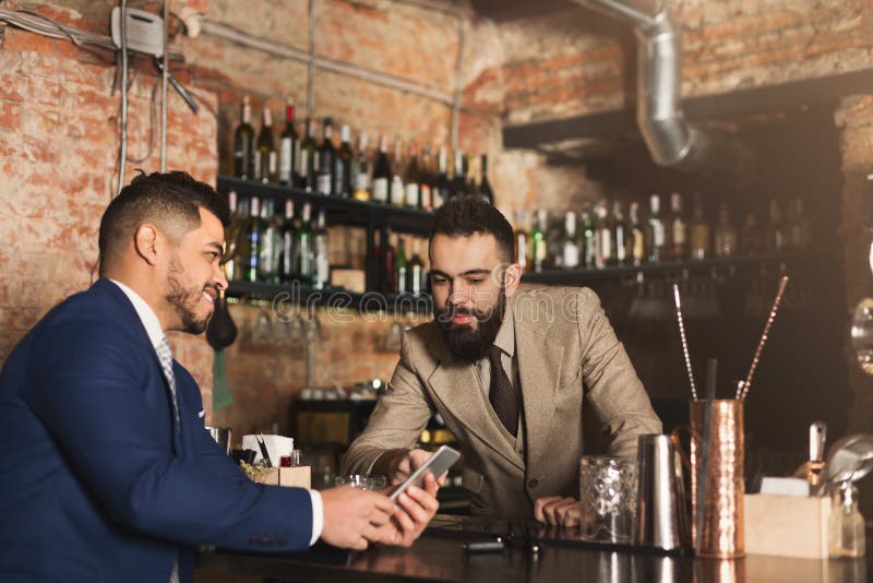 Biznesmen pokazuje informację na telefonie barman obrazy stock Biznesmen pokazuje informację na telefonie barman obrazy stock