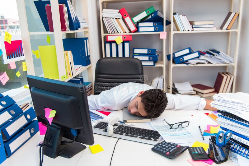 Biznesmen pracuje w biurze z stosami książki i papiery obraz stock Biznesmen pracuje w biurze z stosami książki i papiery obraz stock