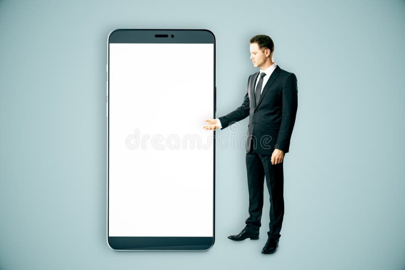 Biznesmen prezentujący gigantyczny smartfon z białym ekranem fotografia royalty free