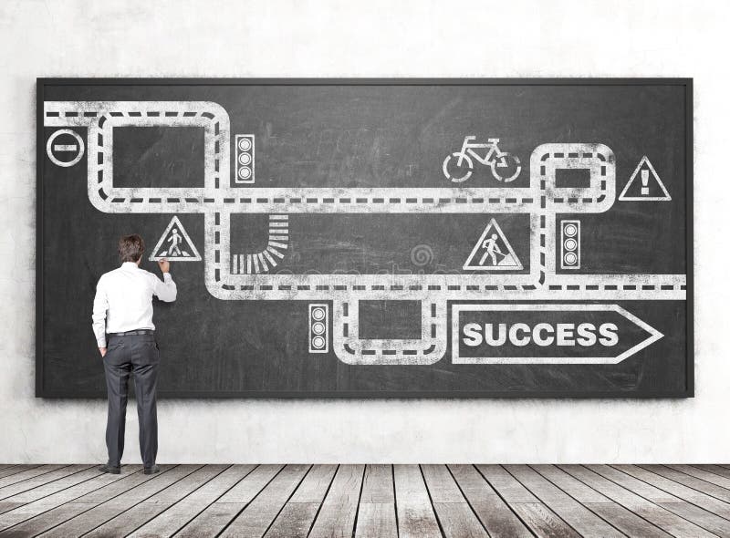 Businessman drawing road to success sketch on chalkboard hanging in room with concrete wall and wooden floor. Businessman drawing road to success sketch on chalkboard hanging in room with concrete wall and wooden floor