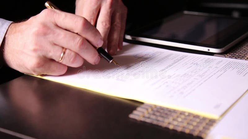 Biznesmen siedzi biurowego biurko podpisuje rachunek porównuje one, z komputer osobisty pastylką zakończenie ręki mężczyzna i fon