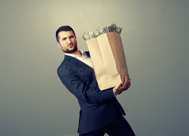 Biznesmen trzyma ciężką papierową torbę zdjęcia stock Biznesmen trzyma ciężką papierową torbę zdjęcia stock