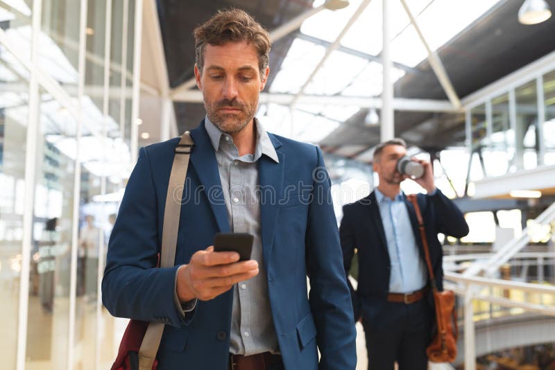 Biznesmen używa telefon komórkowego w korytarzu podczas gdy chodzący fotografia royalty free Biznesmen używa telefon komórkowego w korytarzu podczas gdy chodzący fotografia royalty free