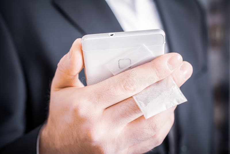 Biznesmen W kostiumu Chuje Troszkę torbę leki Z bielu proszkiem Za Jego telefonem komórkowym fotografia royalty free Biznesmen W kostiumu Chuje Troszkę torbę leki Z bielu proszkiem Za Jego telefonem komórkowym fotografia royalty free