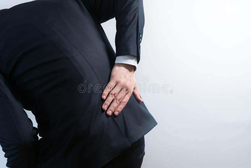 Biznesmen w kostiumu ma backache Zginać w bólu z rękami trzyma niskimi z powrotem zdjęcia royalty free Biznesmen w kostiumu ma backache Zginać w bólu z rękami trzyma niskimi z powrotem zdjęcia royalty free