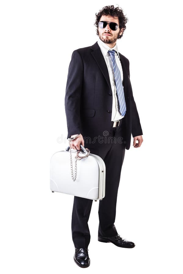 Businessman wearing a suit with a secure suitcase attached with handcuffs isolated over a white background. Businessman wearing a suit with a secure suitcase attached with handcuffs isolated over a white background