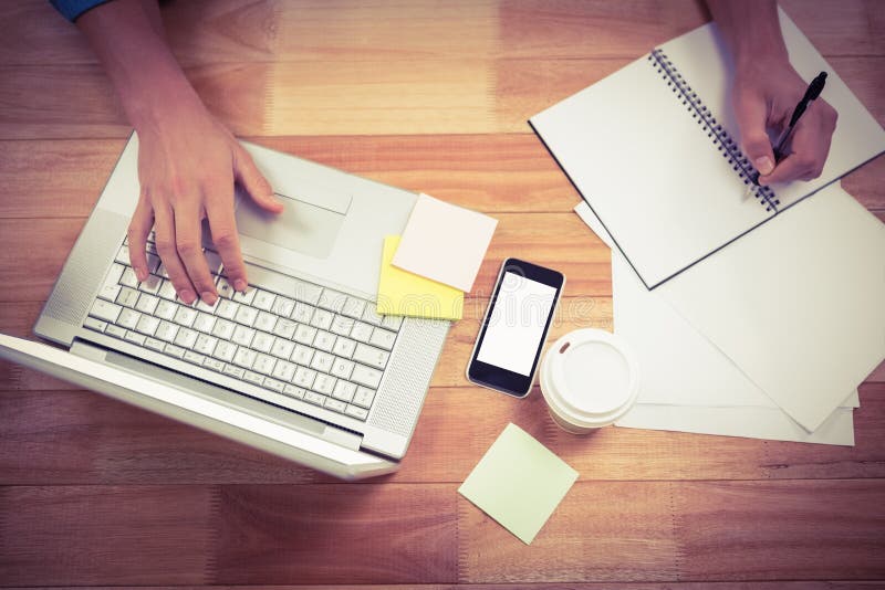 Biznesmena writing na spirala książkowym używa laptopie zdjęcie stock Biznesmena writing na spirala książkowym używa laptopie zdjęcie stock