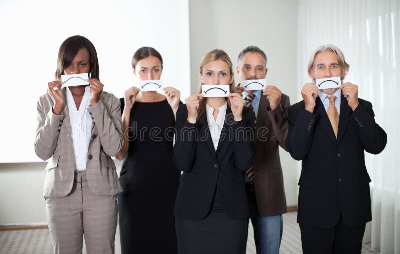 Diverse group of business people holding a card with sad sign by their faces. Diverse group of business people holding a card with sad sign by their faces.