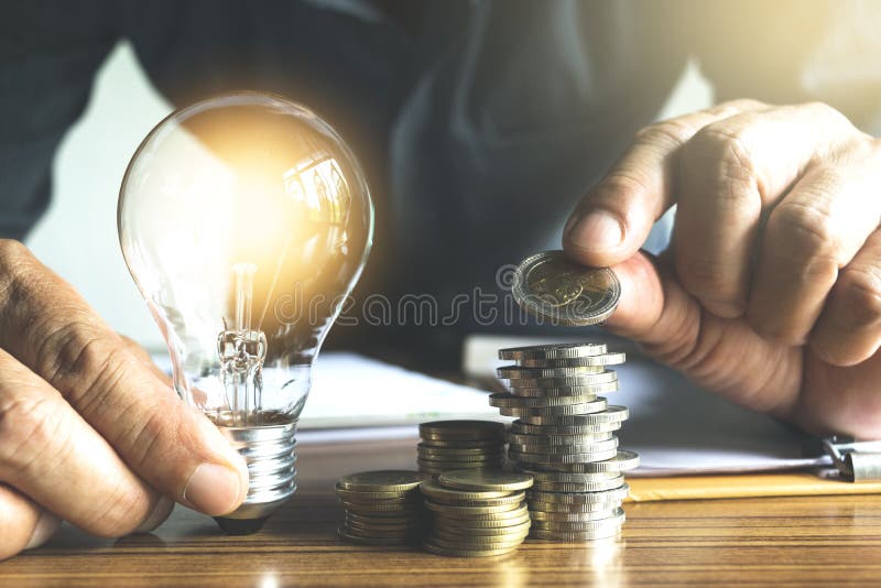Biznesowego mężczyzna mienia żarówka na biurku w biurze i writin zdjęcia stock Biznesowego mężczyzna mienia żarówka na biurku w biurze i writin zdjęcia stock