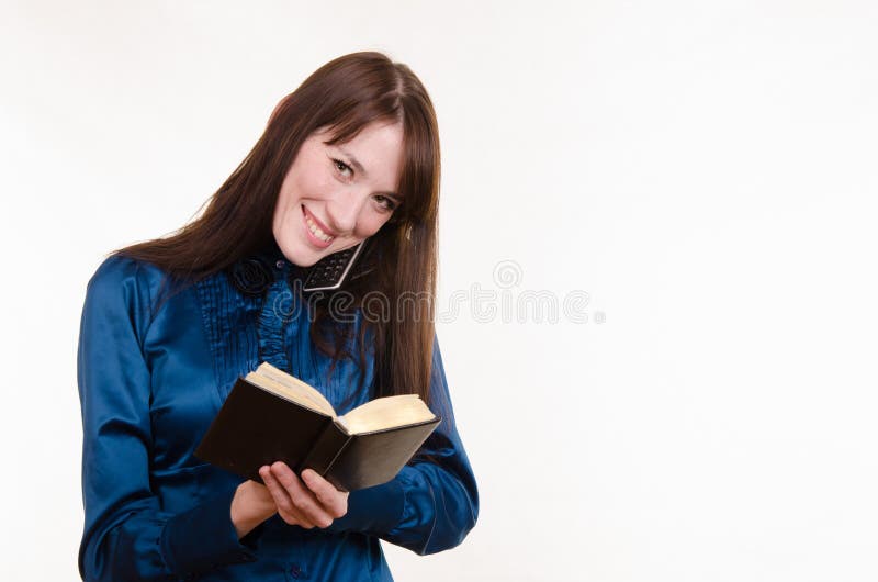 Beautiful young girl talking on the phone and writes notes in notebook. Beautiful young girl talking on the phone and writes notes in notebook