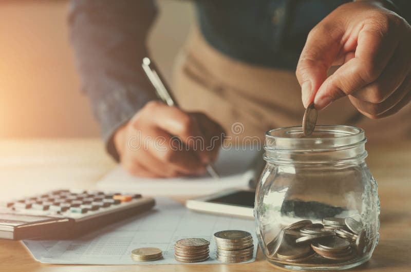 business accountin with saving money with hand putting coins in jug glass concept financial. business accountin with saving money with hand putting coins in jug glass concept financial