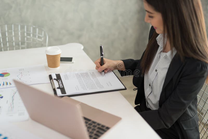 Bizneswoman podpisuje kontraktacyjnego papier w jej workstatio przy pracą obraz royalty free Bizneswoman podpisuje kontraktacyjnego papier w jej workstatio przy pracą obraz royalty free