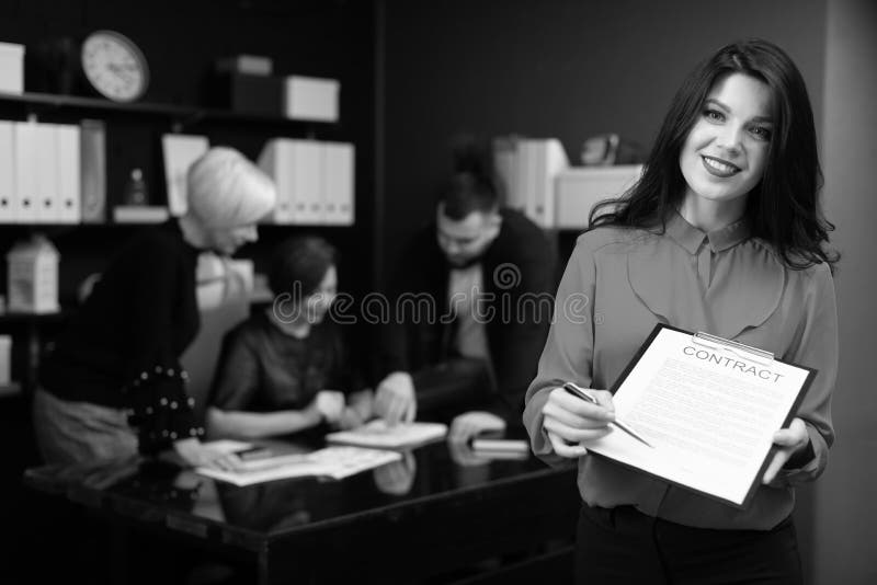 Bizneswoman z piórem i kontrakt na tle urzędnicy dyskutujemy projekt fotografia royalty free Bizneswoman z piórem i kontrakt na tle urzędnicy dyskutujemy projekt fotografia royalty free