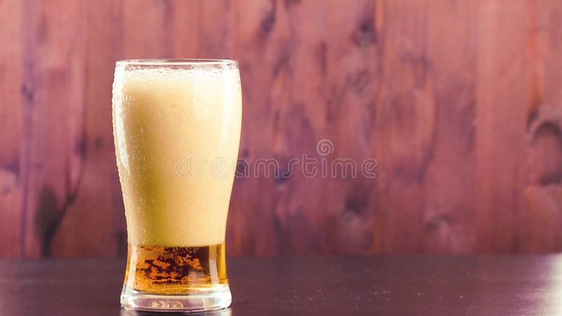 Bière de versement en verre avec la mousse blanche sur le bois