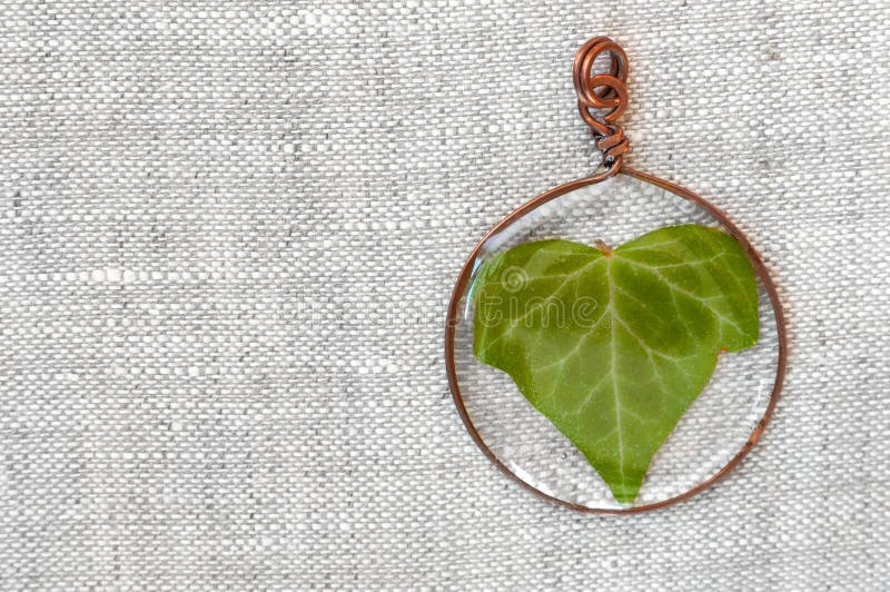 Handmade epoxy resin jewelry. pendant, ivy leaf in copper frame. background. place for inscription. Handmade epoxy resin jewelry. pendant, ivy leaf in copper frame. background. place for inscription