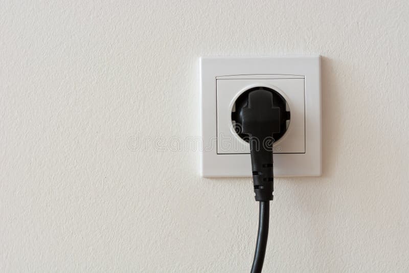 Black 220 volt power plug plugged in a socket royalty free stock photo