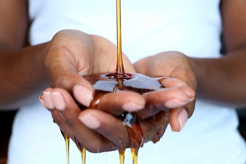 Black african indian manicured hands cupped holding honey which drips and pours out. Against a white background. honey is used in beauty treatments. Black african indian manicured hands cupped holding honey which drips and pours out. Against a white background. honey is used in beauty treatments