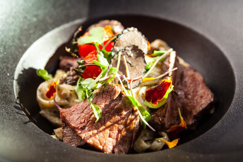 Black Angus beef tagliatelle pasta with fresh black truffles and parmegano. Delicious healthy traditional food closeup served for lunch in modern gourmet cuisine restaurant.