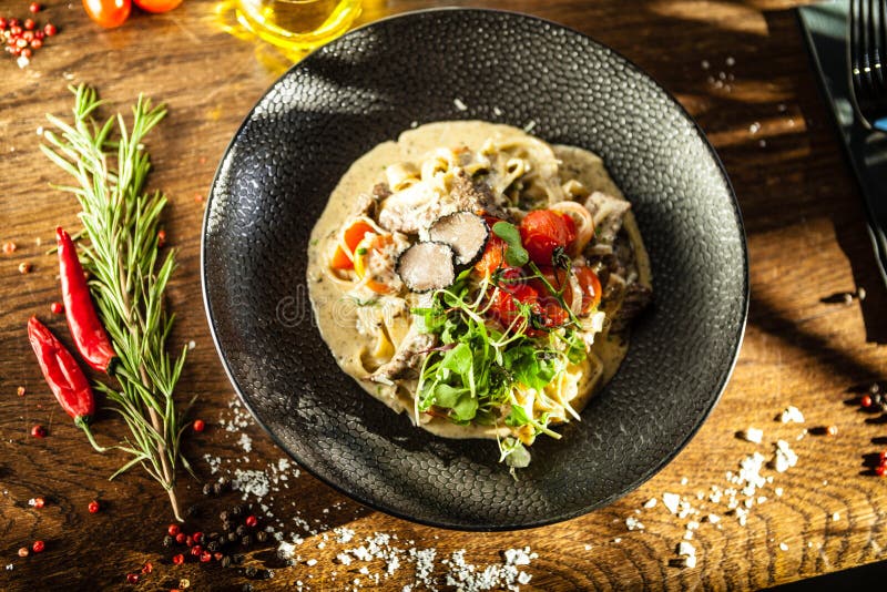 Black Angus beef tagliatelle pasta with fresh black truffles and parmegano. Delicious healthy traditional food closeup served for lunch in modern gourmet cuisine restaurant.