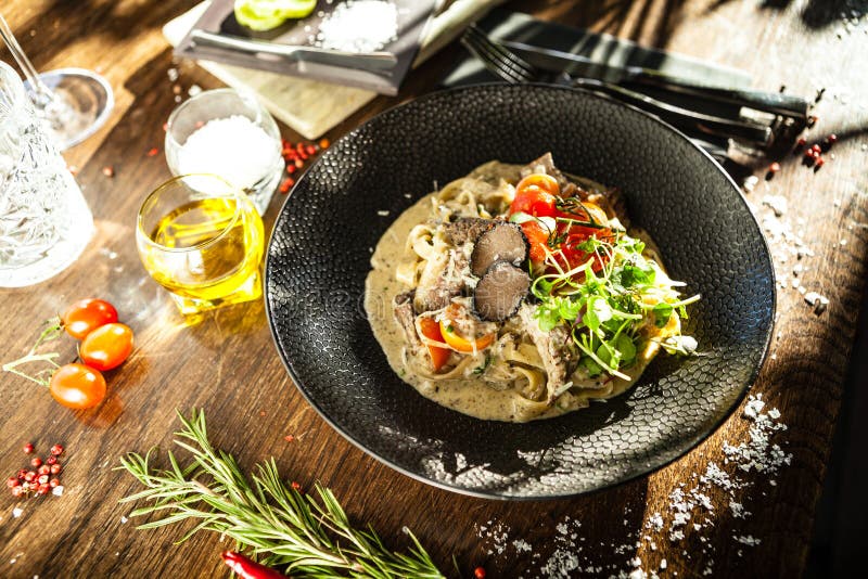 Black Angus beef tagliatelle pasta with fresh black truffles and parmegano. Delicious healthy traditional food closeup served for lunch in modern gourmet cuisine restaurant.