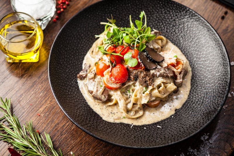 Black Angus beef tagliatelle pasta with fresh black truffles and parmegano. Delicious healthy traditional food closeup served for lunch in modern gourmet cuisine restaurant.